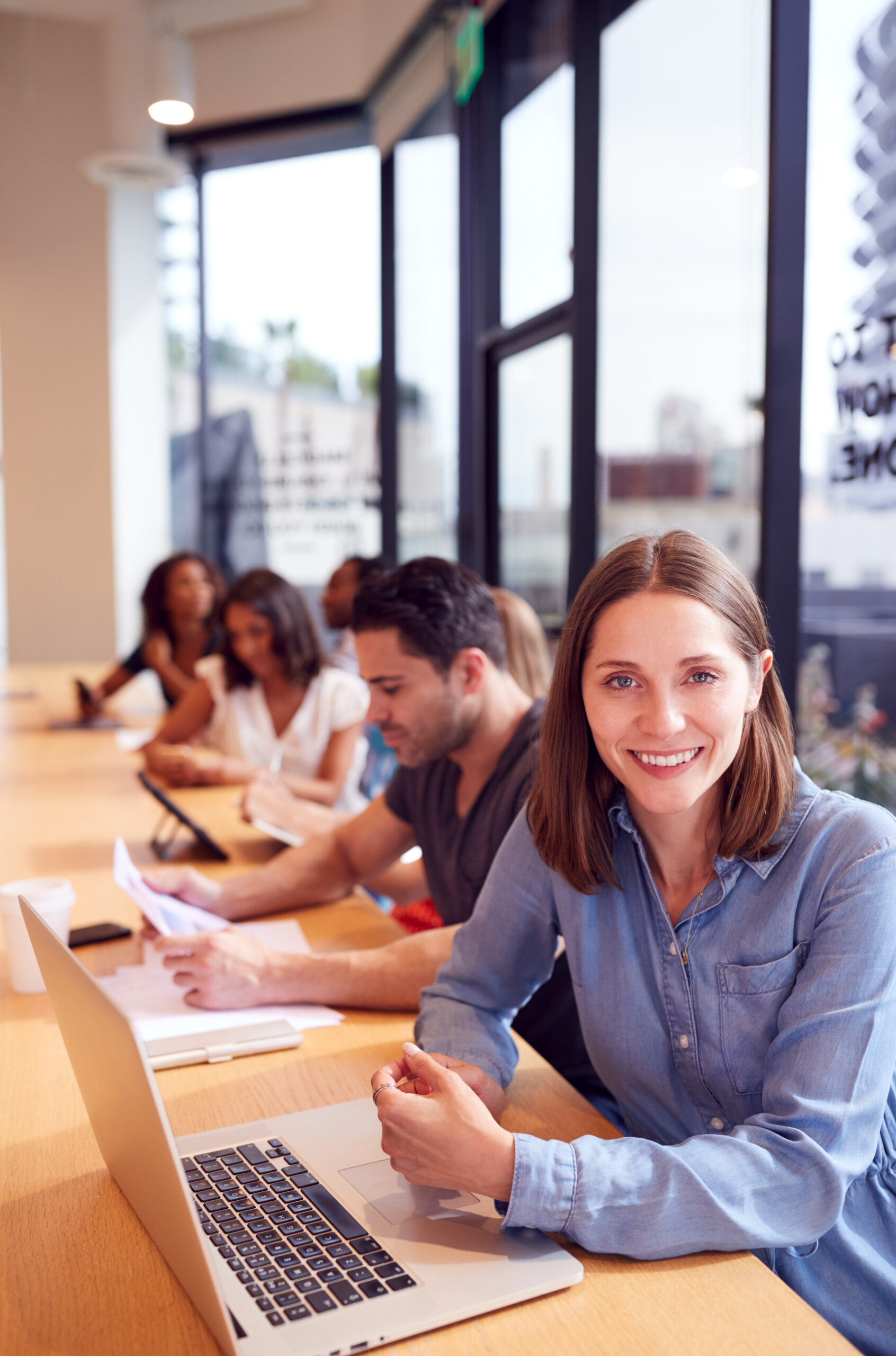 Portrait Of Businesswoman Working At Desk In Shared Open Plan Office Workspace